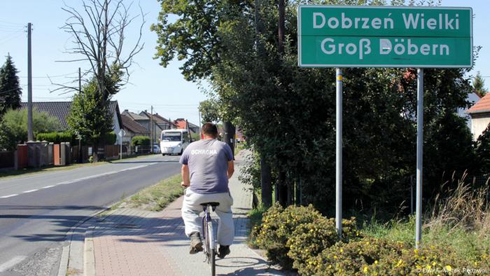 Mężczyzna jedzie na rowerze, który minął znak na Dobrzeń Wielki 