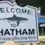 Wooden sign with bites taken out of it - reads Welcome to Chatham, home of the Great White
