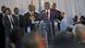 Vital Kamerhe speaking on a podium, surrounded by a group of men Vital Kamerhe speaking on a podium, surrounded by a group of men