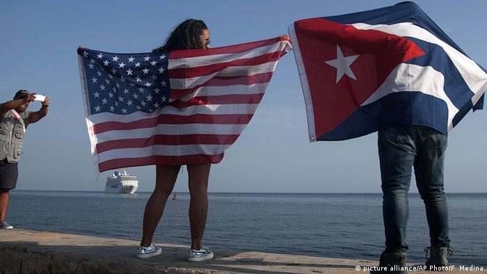 Foto simbólica de dos personas que sostienen banderas de Estados Unidos y Cuba en La Habana.