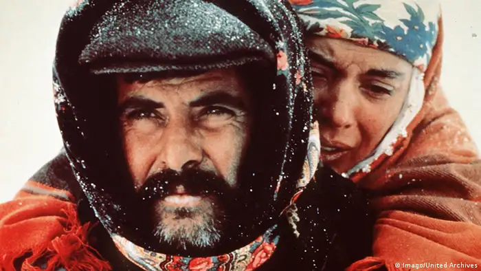 Szene aus Yol - Der Weg mit Tarik Akan Yol, Darsteller, der eine Frau Huckepack auf dem Rücken trägt, Schneeszene (Foto: Imago/United Archives)