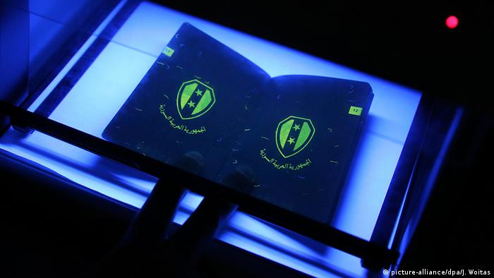 Паспорт беженца проходит проверку в ультрафиолетовом свете в миграционном ведомстве Германии