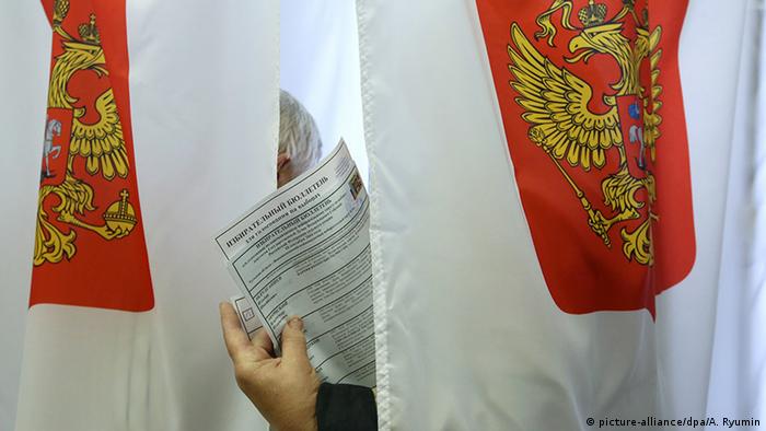 Символическая картинка: рука с бюллетенем для голосования на выборах в России