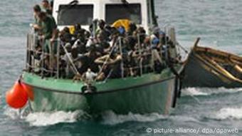 Ein Boot der spanischen Küstenwache bringt afrikanische Füchtlinge nach Fuerteventura, das Wrack des heruntergekommenen Bootes im Schlepptau.