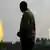 An unidentified man stands near a gas flare belonging to the Agip Oil company in Idu Ogba, Niger Delta area