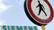 A man walks by a Siemens sign. A man walks by a Siemens sign.