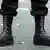 We can see a person, seen from the knees down, wearing Doc Marten boots