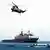 Ein NATO-Kriegsschiff umgeben von kleinen Landungsbooten, darüber fliegt ein Kampfhubschrauber (Foto: AP)