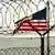 An American flag waves in the breeze behind razor-wire at Camp Delta