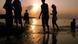 People walk along the beach at sunset People walk along the beach at sunset
