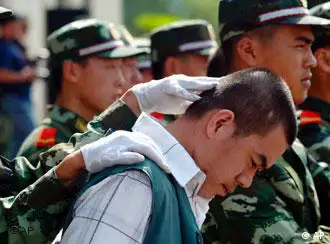 A Chinese paramilitary officer keeps the head of a drug dealer bowed during a public sentencing to mark International Day against Drug Abuse and Illicit Drug Trafficking in Hangzhou, eastern China's Zhejiang province, Monday, June 26, 2006. Chinese drug control officials said Thursday their yearlong war on drugs has severely squeezed heroin supplies from the Golden Triangle. Officials also announced the arrest of some 46,000 drug suspects and the seizure of some 6.9 tons of heroin last year. During the trial in Hangzhou, 20 drug dealers were sentenced today with three given the death penalty and executed soon after. (AP Photo) ** CHINA OUT **