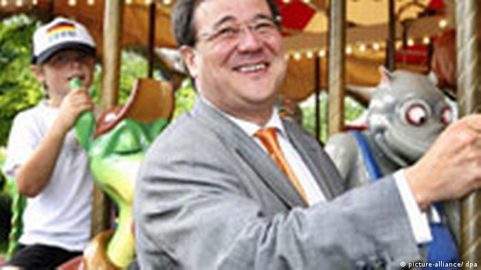 A smiling Armin Laschet riding a merry-go-round