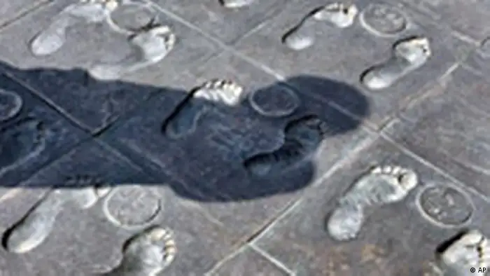 The shadow of a visitor is cast on carvings of foot prints of survivors of Nanjing Massacre on March 31, 2005 at Nanjing Massacre Memorial Hall in Nanjing, China. At the Nanjing Massacre Memorial Hall, signs of Japanese wartime atrocities are everywhere. Gory photos and engraved stone tablets exhort visitors to remember that past and hold Tokyo to account. Now, the Internet is doing the same job, only much faster. In recent weeks, organizers claim to have collected more than 24 million names on an Internet petition demanding that Japan be denied a permanent U.N. Security Council seat, claiming it has failed to apologize for wartime aggression against China. (AP Photo/Eugene Hoshiko)