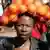 Eine Südafrikanerin trägt einen Sack mit Orangen auf dem Kopf