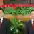 Präsident Hu Jintao (l.) und Premierminister Wen Jiabao stehen in einem halben Meter Abstand vor einer Reihe roter Blumen