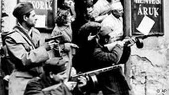 Schießende Männer vor einem Einkaufsladen am 2.11.1956