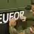 A Bundeswehr soldier pastes a EUFOR symbol on a military vehicle