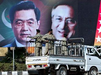 Paramilitärs in einem Lastwagen vor einem großen Plakat, das Hu und Musharraf zeigt