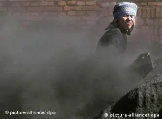 ARCHIV - Staubig: Ein Arbeiter schaufelt grobkörnige Kohle in die Mühle einer Kohlefabrik in Peking (Archivfoto vom 20.10.1999). Am Freitag (02.02.2007) wird in Paris der neue Bericht des UN-Klimarats (IPCC) vorgestellt. Foto: Stephen Shaver +++(c) dpa - Bildfunk+++