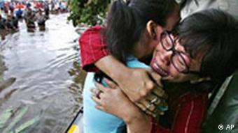 Indonesische Frau umarmt ihre Verwandte, nachdem sie aus ihrem überschwemmten Haus gerettet wurde