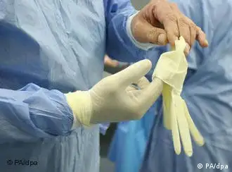A doctor puts on gloves in an operating room