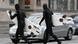 Two surfers in wetsuits cross a busy street with their surfboards Two surfers in wetsuits cross a busy street with their surfboards