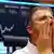 A stock trader wipes his face in front of the German Stock Index