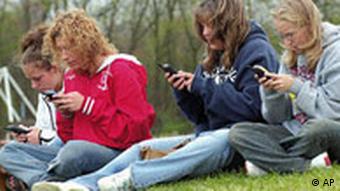 Vier jugendliche Mädchen sitzen auf der Wiese und schreiben Nachrichten mit ihrem Handy. (AP Photo)