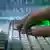 Ein Hand auf einer Tastatur. Im Hintergrund sind einser und Nuller in grüner SChrift auf einen Wand projeziert.