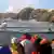 Das Schiff auf Schlagseite, im Vordergrund Touristen in Rettungswesten