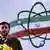 Iranian President Mahmoud Ahmadinejad in front of flag with atomic symbol