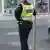 Policajac stoji naslonjen na prometni znak