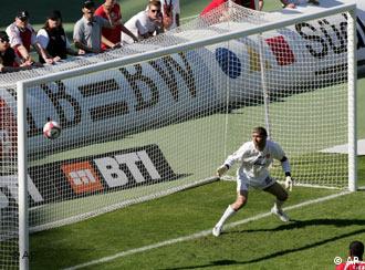 A goalkeeper watches a ball go into goal