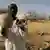 A man in Darfur holds up a human skull