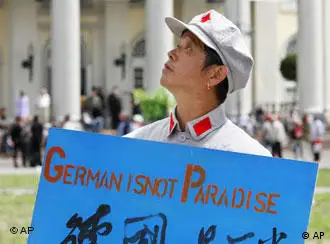 6月16日开幕时，一名中国艺术家头戴红军帽手持德国标语“德国不是天堂”