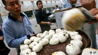 Customers buy steamed buns, called baozi, at a sidewalk stall in Beijing Thursday July 12, 2007. An undercover investigation by a Chinese TV crew found that chopped cardboard, softened in an industrial chemical and made tasty with pork flavoring, is a main ingredient in batches of baozi sold in a Beijing neighborhood. (AP Photo/Greg Baker)