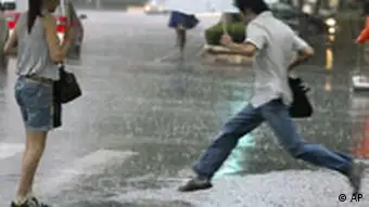 A pedestrian jumps over a flooded road as it rains in Shanghai, eastern China, Tuesday, Sept. 18, 2007. China's commercial center of Shanghai was evacuating 200,000 people on Tuesday ahead of the expected arrival of Typhoon Wipha, potentially the most destructive storm to hit the city in a decade. (AP Photo/EyePress) CHINA OUT