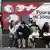 Menschen sitzen vor einem SVP-Wahlplakat (Foto: dpa)
