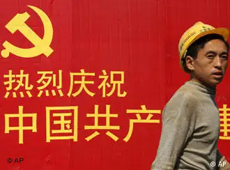 A construction worker walks past an official propaganda of Chinese Communist Party Friday Oct. 19, 2007 in Shanghai, China. Chinese Communist Party leaders have kept out of the public eye this week in a possible sign of deepening closed-door deliberations over appointments that will determine China's leadership and influence policy-making for the next five years. (AP Photo/Eugene Hoshiko)