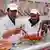 Two halal butchers holding up sausages
