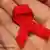 A hand holds a red AIDS ribbon
