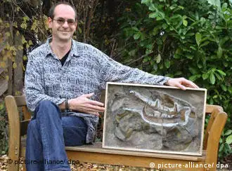 Scientist Markus Poschmann sits outside, holding the giant scorpion claw he excavated