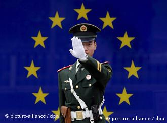 A Chinese paramilitary police officer reacts to having his photograph taken in front of the image of the European Union (EU) flag at the EU embassy in Beijing, China