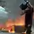 A man running across the road holding a looted gas cylinder from a shop in Mombasa, Kenya, with fire in background