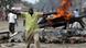 Anhänger der Opposition in Kisumu vor brennendem Autowrack (Quelle: AP) Anhänger der Opposition in Kisumu vor brennendem Autowrack (Quelle: AP)
