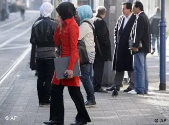 Women in headscarves wait at a bus stop