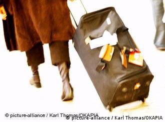 Eine Person, die nur von der Hüfte abwärts zu sehen ist, zieht einen großen Koffer hinter sich her. Das Motiv steht symbolisch für das Thema Reisen. (Foto: Picture Alliance / Karl Thomas / OKAPIA)