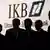 Five people silhouetted in front of an IKB sign