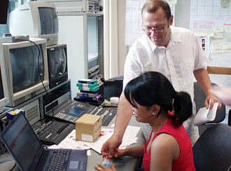 Two journalists in front of a laptop