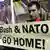 Protestor holding banner reading "Bush & NATO go home!"